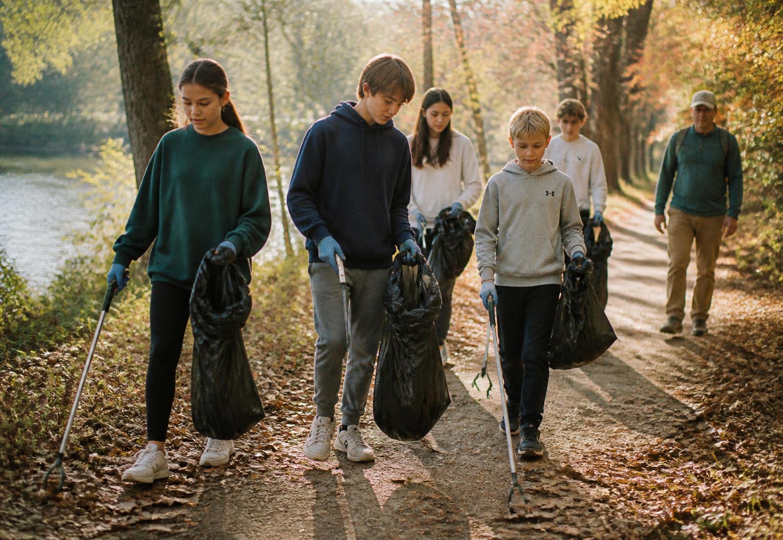Student volunteers picking up litter along a park greenway with an adult chaperone